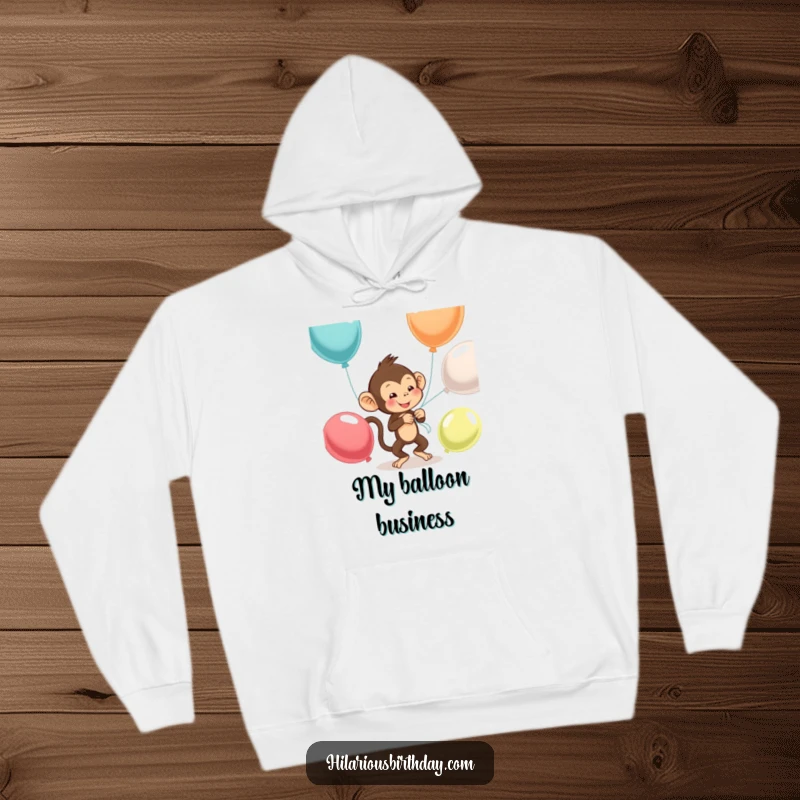 Funny monkey hoodie depicting a mischievous monkey entangled in balloons it's trying to tie, adding warmth and humor.